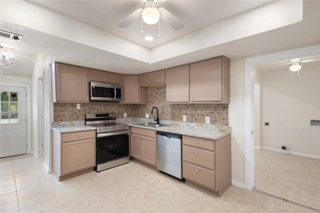 kitchen with light stone counters, ceiling fan, decorative backsplash, sink, and appliances with stainless steel finishes