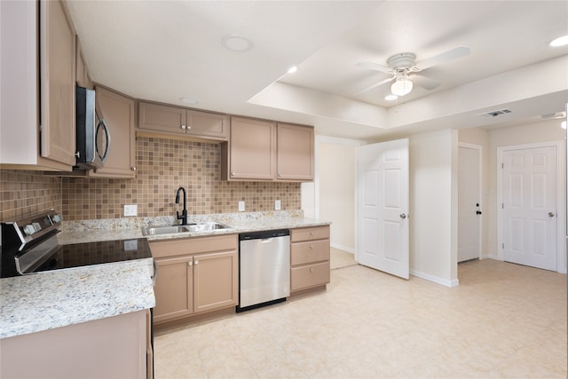 kitchen featuring ceiling fan, sink, appliances with stainless steel finishes, light stone countertops, and decorative backsplash