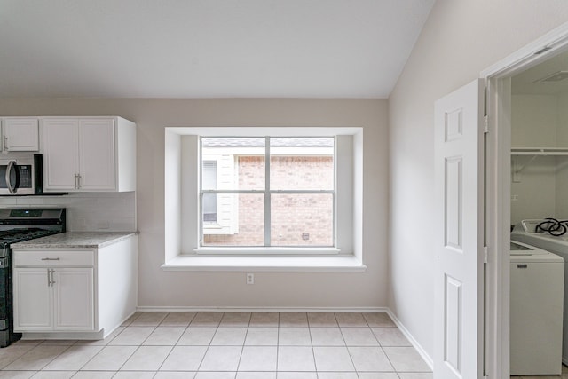 kitchen featuring range, backsplash, washer / clothes dryer, light tile patterned floors, and white cabinets