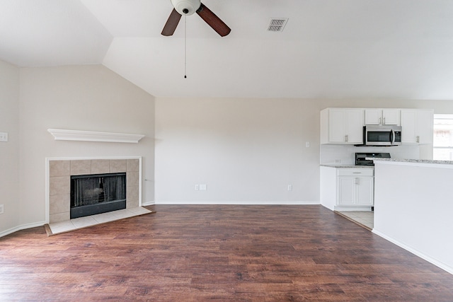 unfurnished living room with ceiling fan, lofted ceiling, hardwood / wood-style flooring, and a tile fireplace