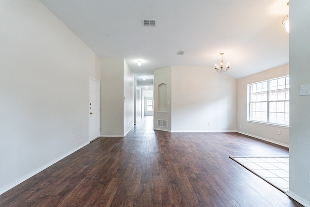 spare room featuring wood-type flooring, vaulted ceiling, and an inviting chandelier