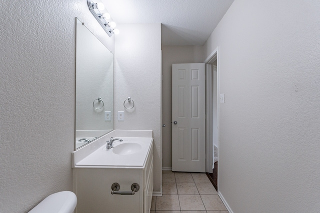 bathroom with a textured ceiling, toilet, vanity, and tile patterned flooring