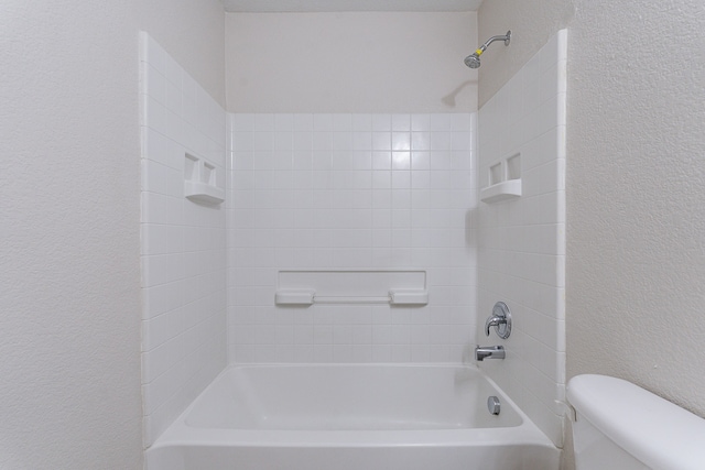 bathroom with toilet and tiled shower / bath