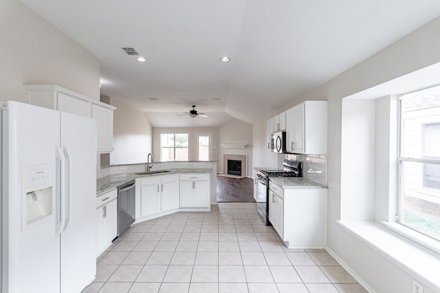 kitchen featuring stainless steel appliances, light wood-type flooring, vaulted ceiling, sink, and kitchen peninsula