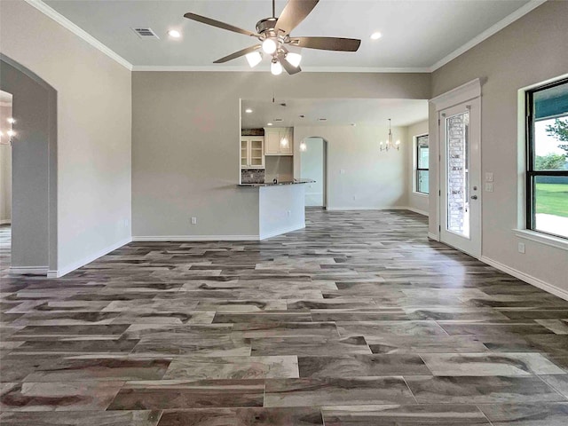 unfurnished living room featuring ceiling fan with notable chandelier and crown molding