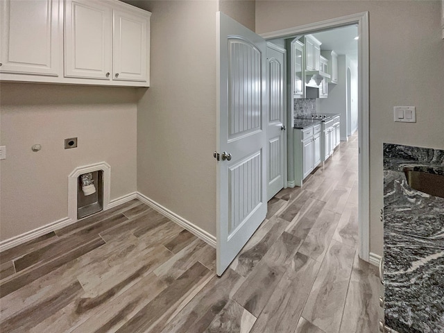 laundry area with hookup for an electric dryer, cabinets, and light hardwood / wood-style floors