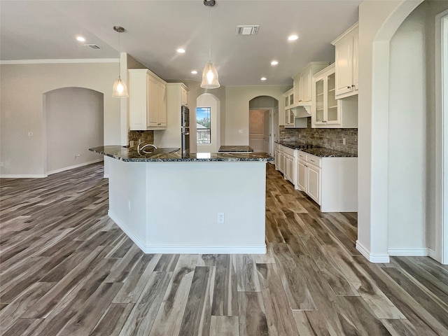 kitchen with dark stone counters, tasteful backsplash, hardwood / wood-style floors, and white cabinetry