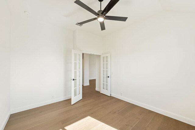 spare room featuring ceiling fan, vaulted ceiling, light wood-type flooring, and french doors