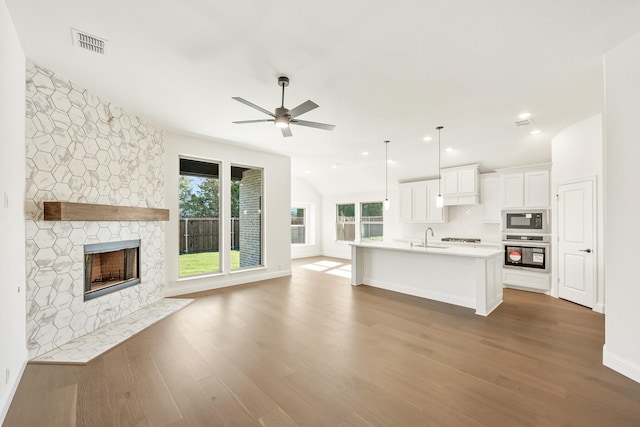 unfurnished living room featuring a fireplace, ceiling fan, sink, and dark hardwood / wood-style floors