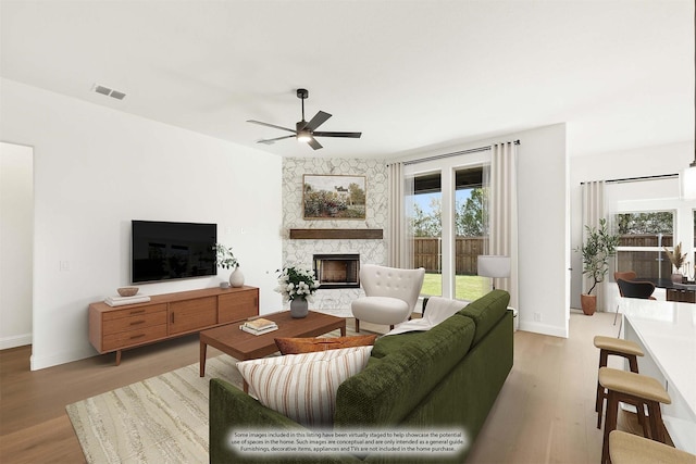 living room featuring a fireplace, ceiling fan, and light hardwood / wood-style flooring