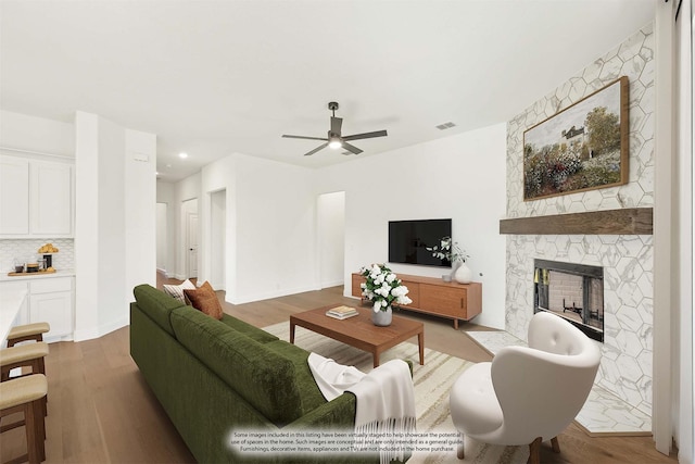 living room with ceiling fan, a fireplace, and hardwood / wood-style flooring