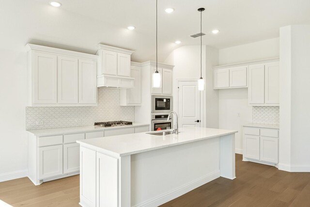 kitchen with wood-type flooring, an island with sink, white cabinetry, and sink