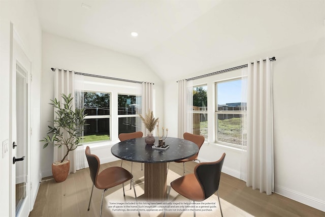 dining area with a healthy amount of sunlight, light wood-type flooring, and vaulted ceiling