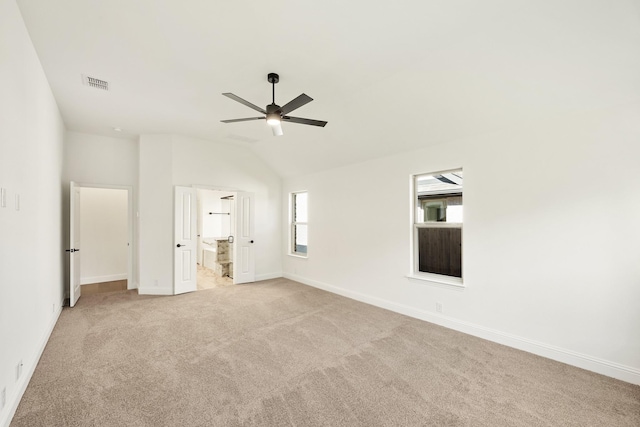 unfurnished bedroom featuring connected bathroom, ceiling fan, light colored carpet, and lofted ceiling