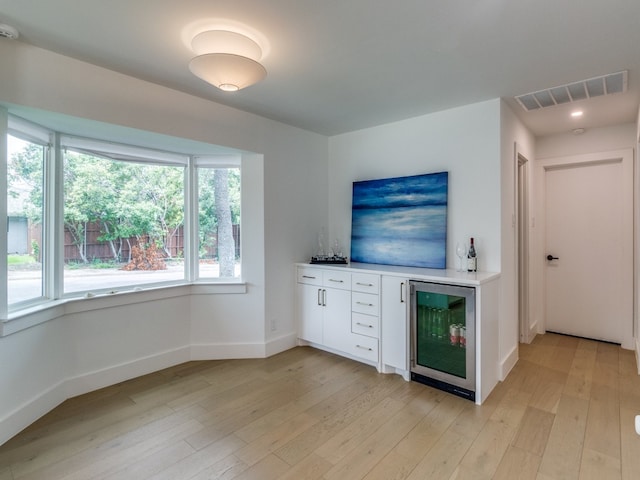 interior space featuring wine cooler, light hardwood / wood-style flooring, and white cabinetry