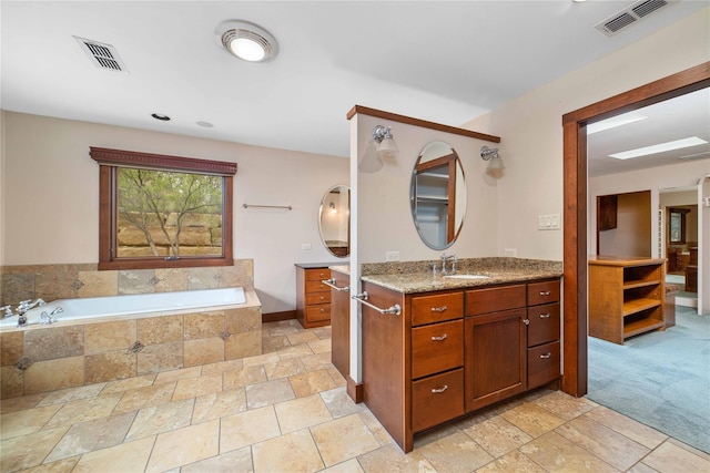 bathroom featuring tile patterned floors, vanity, and a relaxing tiled tub