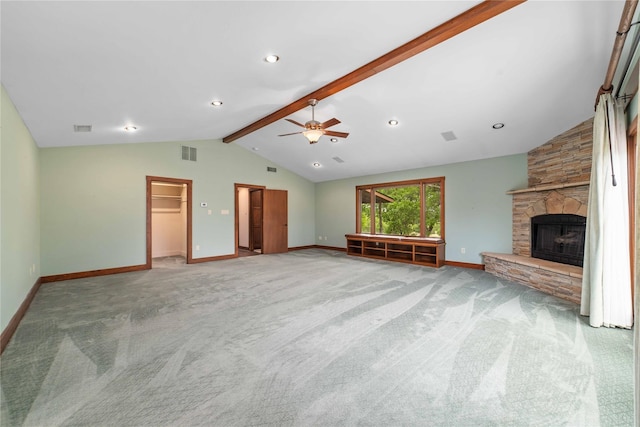 unfurnished living room featuring vaulted ceiling with beams, a stone fireplace, ceiling fan, and light colored carpet