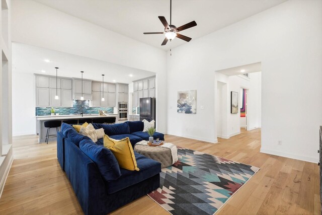 living room featuring light wood-type flooring, sink, and ceiling fan