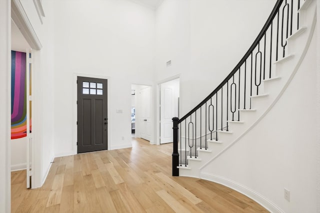 foyer with light hardwood / wood-style flooring and a towering ceiling