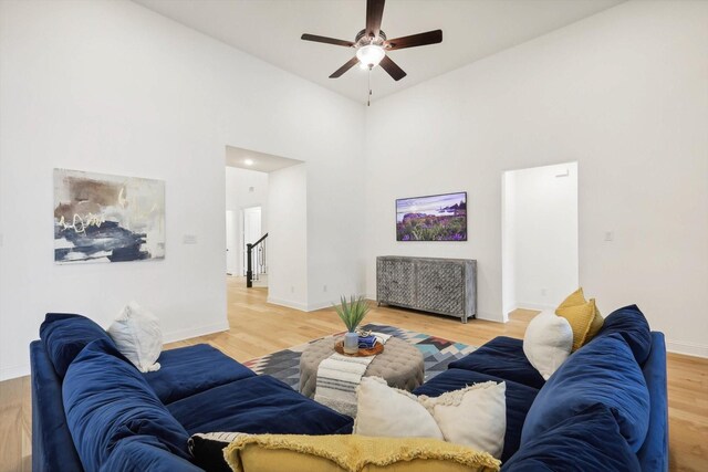 living room featuring a high ceiling, ceiling fan, and light hardwood / wood-style floors