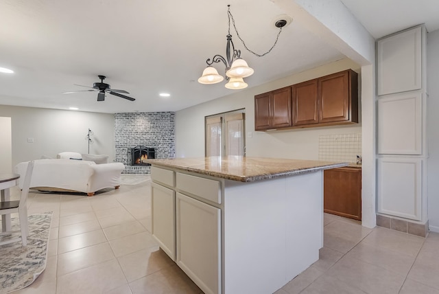 kitchen with backsplash, a center island, hanging light fixtures, and ceiling fan with notable chandelier