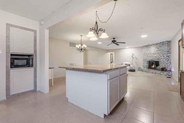 kitchen featuring white cabinets, ceiling fan with notable chandelier, decorative light fixtures, and a kitchen island