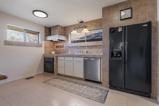 kitchen with pendant lighting, black appliances, sink, light tile patterned floors, and white cabinetry