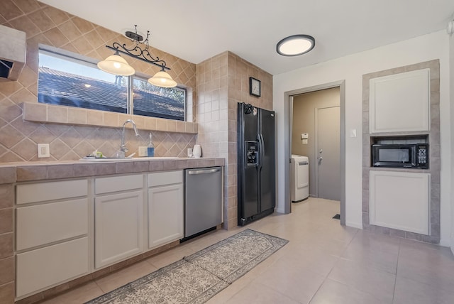 kitchen featuring white cabinetry, sink, pendant lighting, washer / dryer, and black appliances