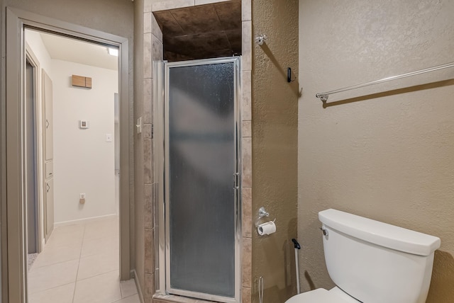 bathroom with tile patterned floors, toilet, and a shower with shower door