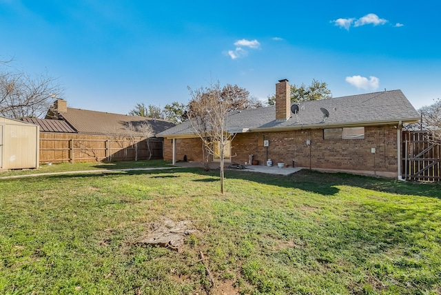 back of house with a patio area, a yard, and a storage unit