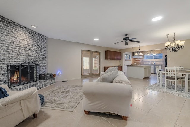 living room with light tile patterned floors, ceiling fan with notable chandelier, a brick fireplace, and french doors