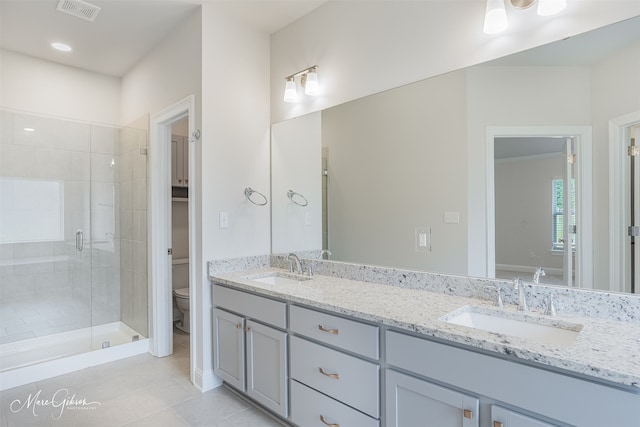 bathroom featuring a shower with shower door, double vanity, tile patterned flooring, and toilet