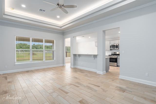 unfurnished living room with a tray ceiling, ceiling fan, and light wood-type flooring