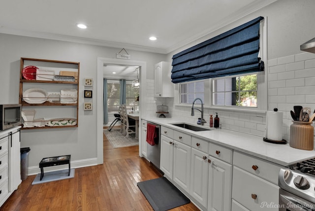 kitchen with tasteful backsplash, crown molding, white cabinetry, hardwood / wood-style flooring, and sink