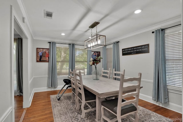 dining space featuring ornamental molding, wood-type flooring, and a chandelier