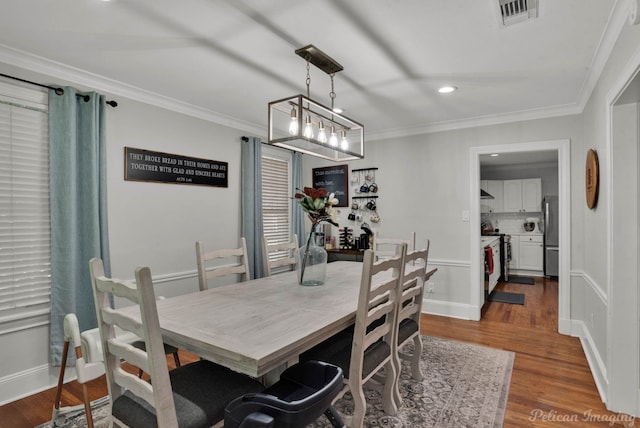 dining room featuring a notable chandelier, crown molding, and hardwood / wood-style flooring