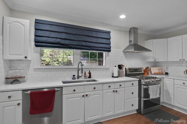 kitchen featuring appliances with stainless steel finishes, white cabinetry, sink, dark hardwood / wood-style floors, and wall chimney range hood