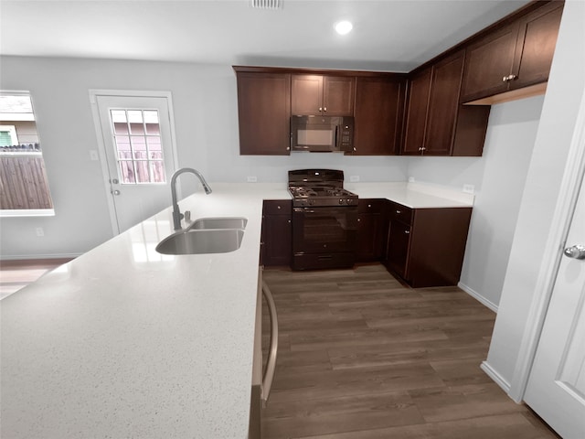 kitchen with dark brown cabinets, wood-type flooring, sink, and gas stove