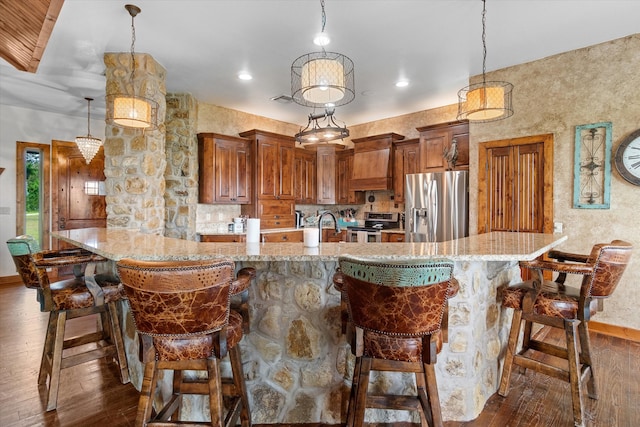 kitchen with appliances with stainless steel finishes, dark hardwood / wood-style flooring, a kitchen breakfast bar, and decorative light fixtures