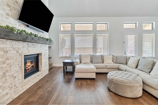 living room with a towering ceiling, a fireplace, and dark hardwood / wood-style floors