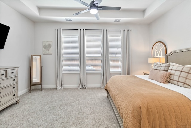 bedroom featuring light carpet, a tray ceiling, and ceiling fan