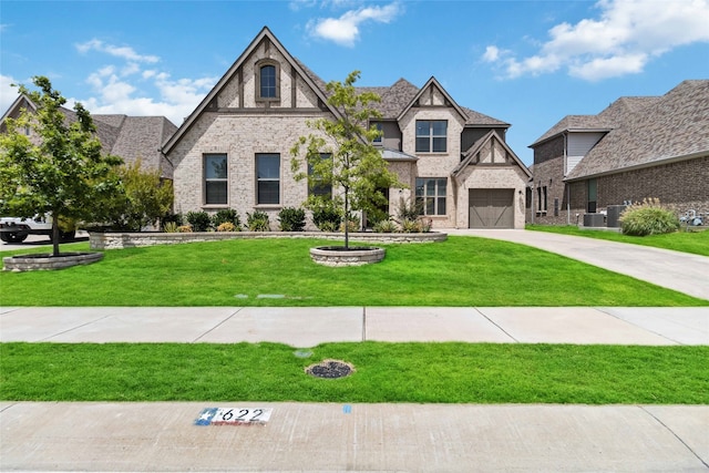 english style home featuring a garage, central air condition unit, and a front lawn