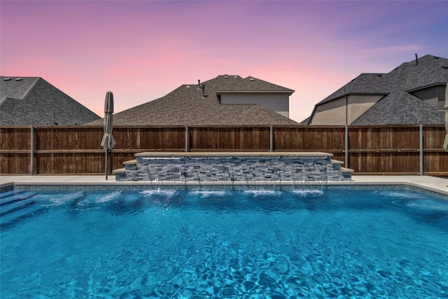 pool at dusk featuring pool water feature