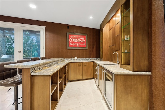 bar with sink, light stone counters, washer / dryer, and light tile patterned floors