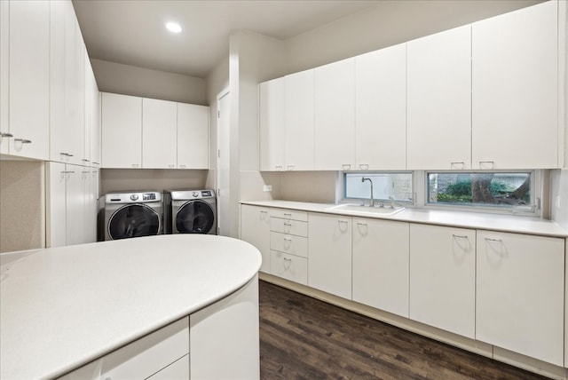 clothes washing area featuring dark wood-type flooring, cabinets, sink, and washer and clothes dryer