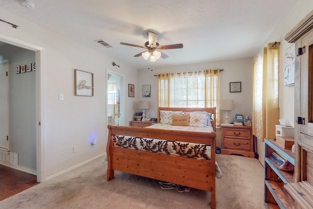 carpeted bedroom with ensuite bathroom and ceiling fan