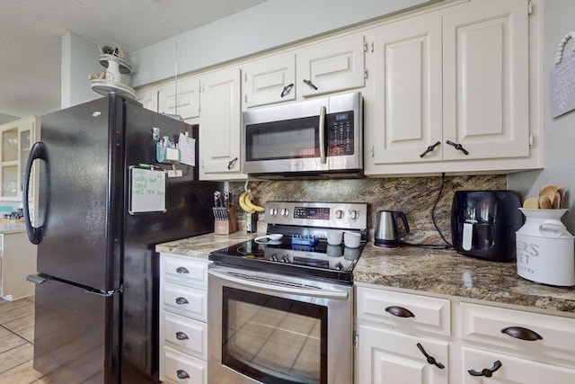 kitchen featuring light tile patterned floors, stainless steel appliances, white cabinetry, and backsplash