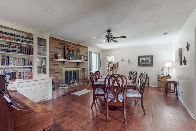 dining area with dark hardwood / wood-style flooring, ceiling fan, a textured ceiling, and a fireplace