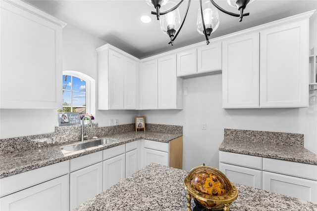 kitchen with white cabinetry, sink, and dark stone countertops