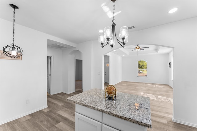 unfurnished dining area with a raised ceiling, ceiling fan, and light hardwood / wood-style floors